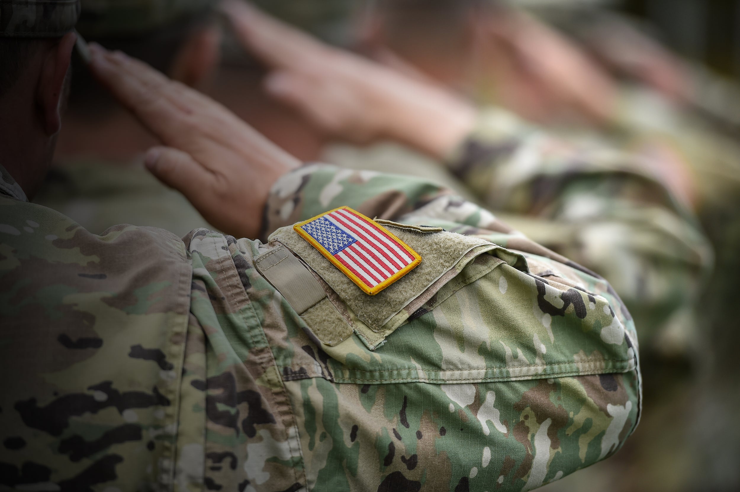 Military guy saluting with an american flag patch on arm